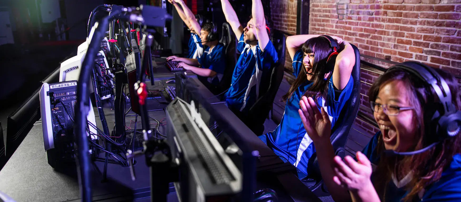 Excited esports players celebrating a victory in a competitive gaming tournament setting.