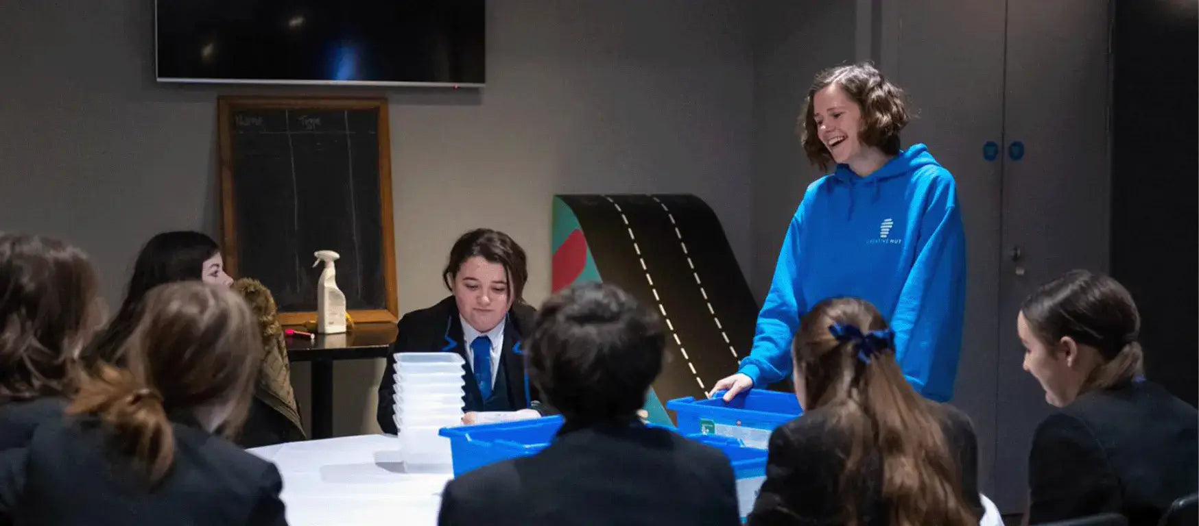 Students engaged in a science workshop at Goodison Park, led by a facilitator in a blue hoodie.
