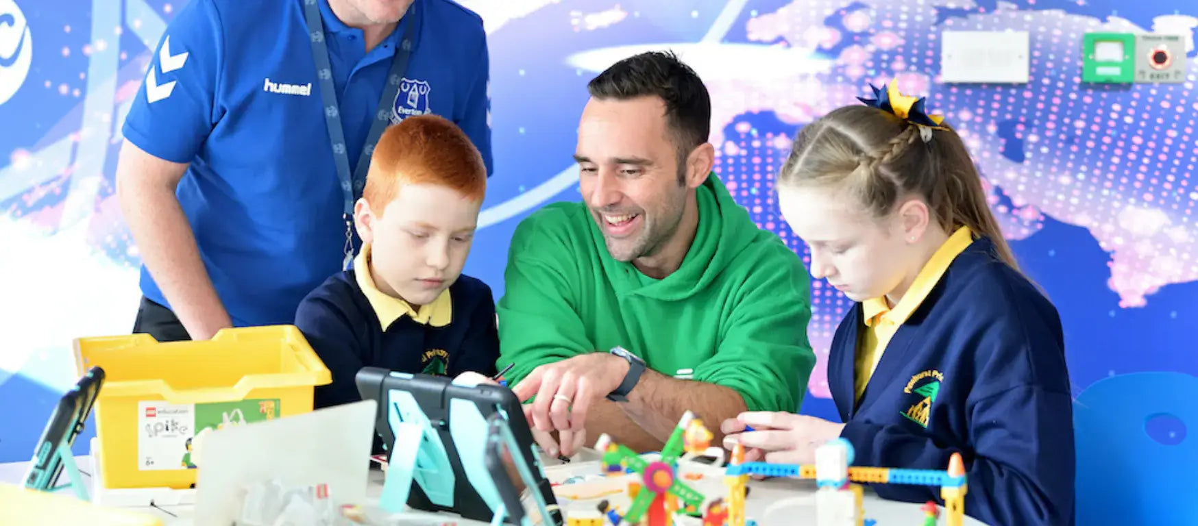 Everton In The Community staff engages with children in digital skills lab, promoting education in Merseyside.