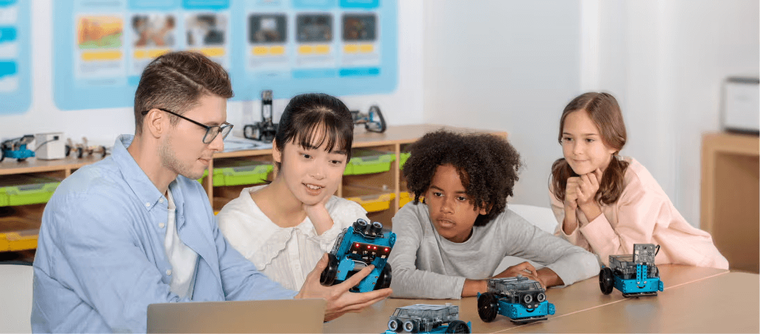 Educator demonstrating coding robots to engaged students in a classroom setting.
