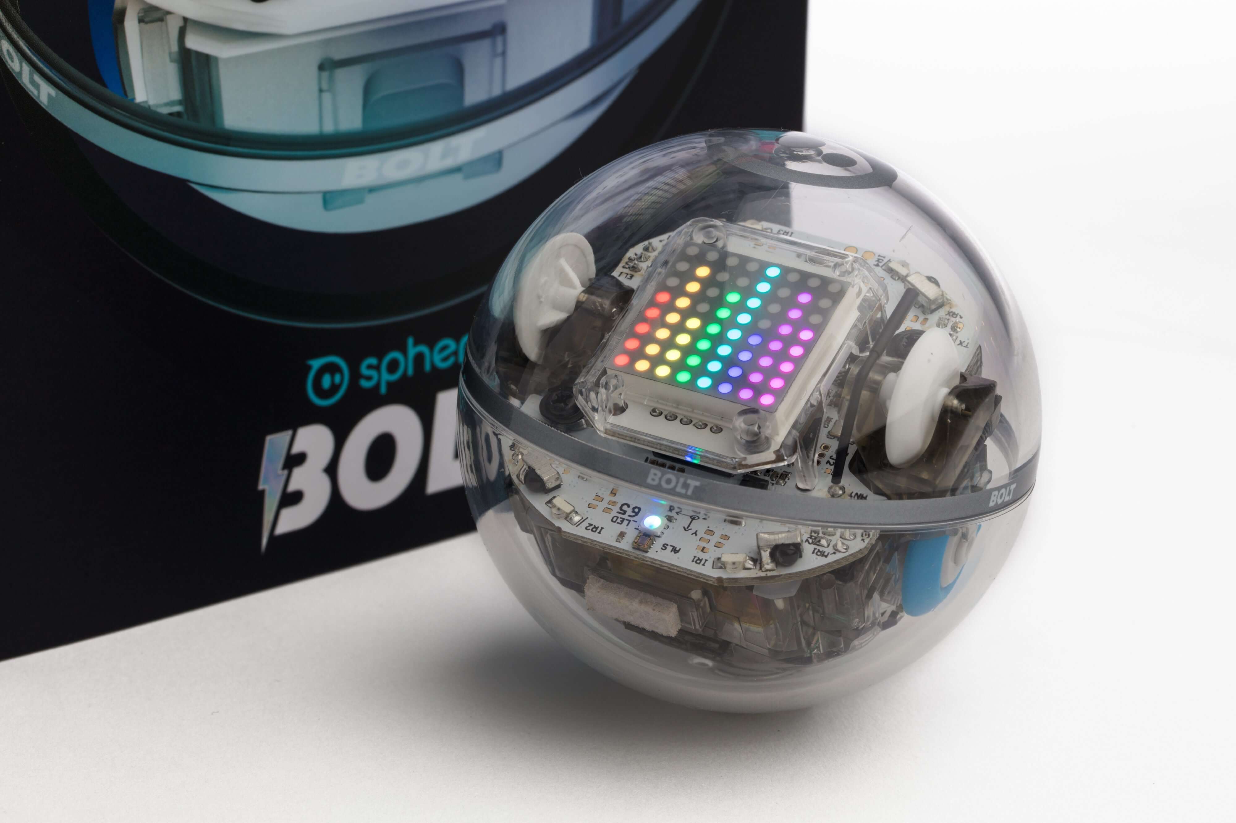 Transparent Sphero Bolt robot with colorful LED lights, next to its packaging.
