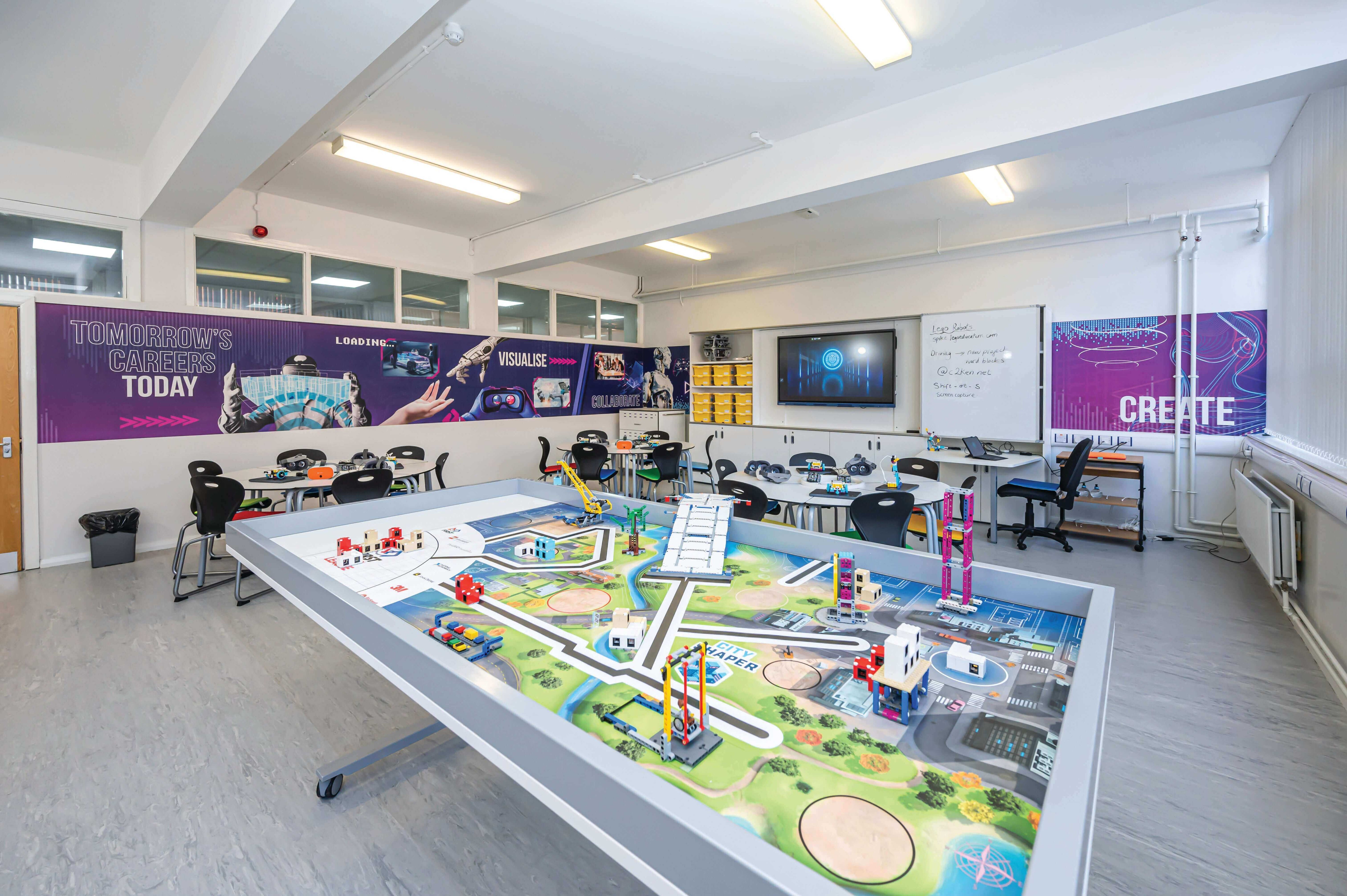 Innovative classroom setup with a large LEGO-style landscape table and tech-focused decor.