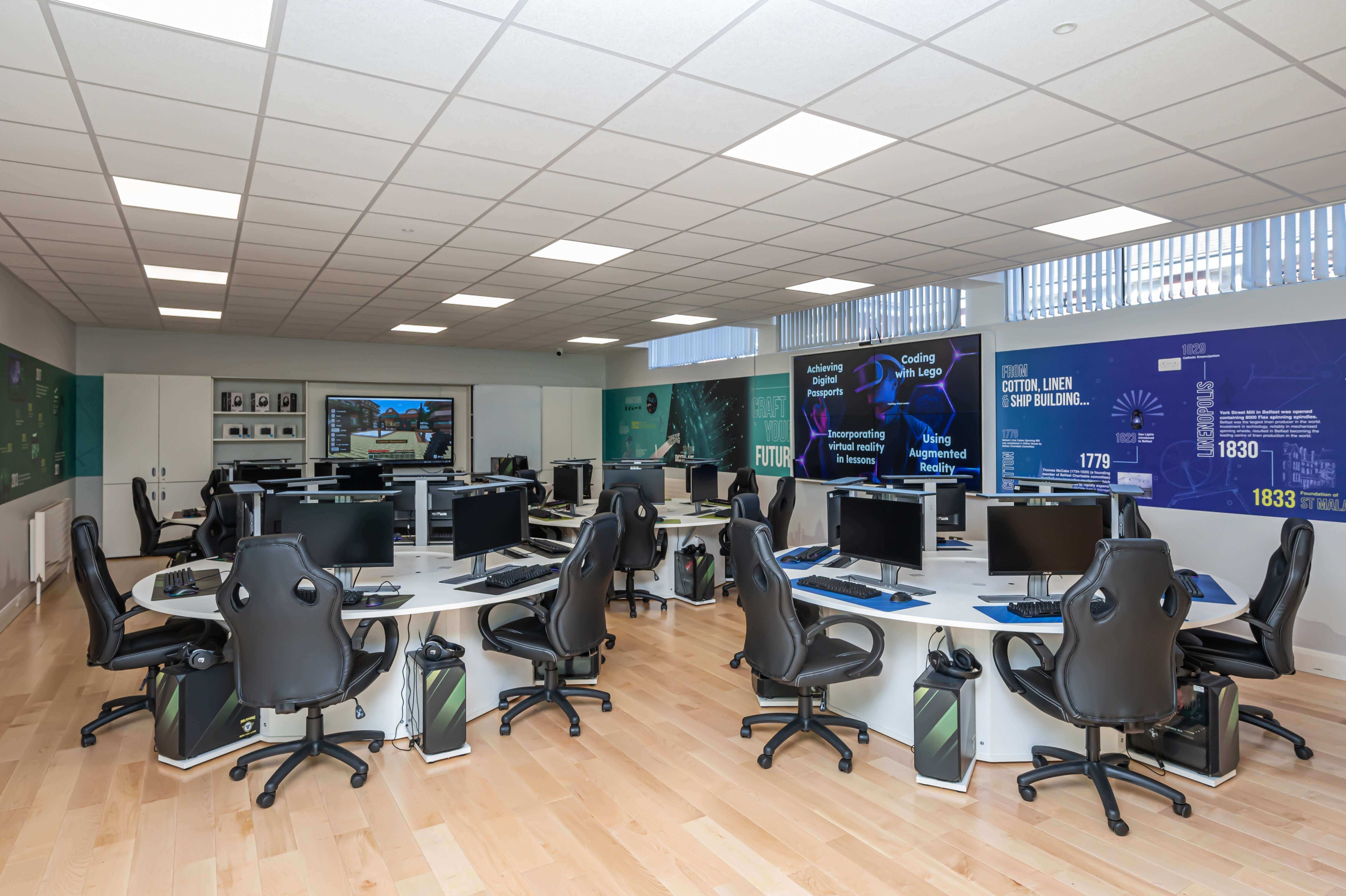 Modern office space featuring multiple computer stations, ergonomic chairs, and engaging wall displays.
