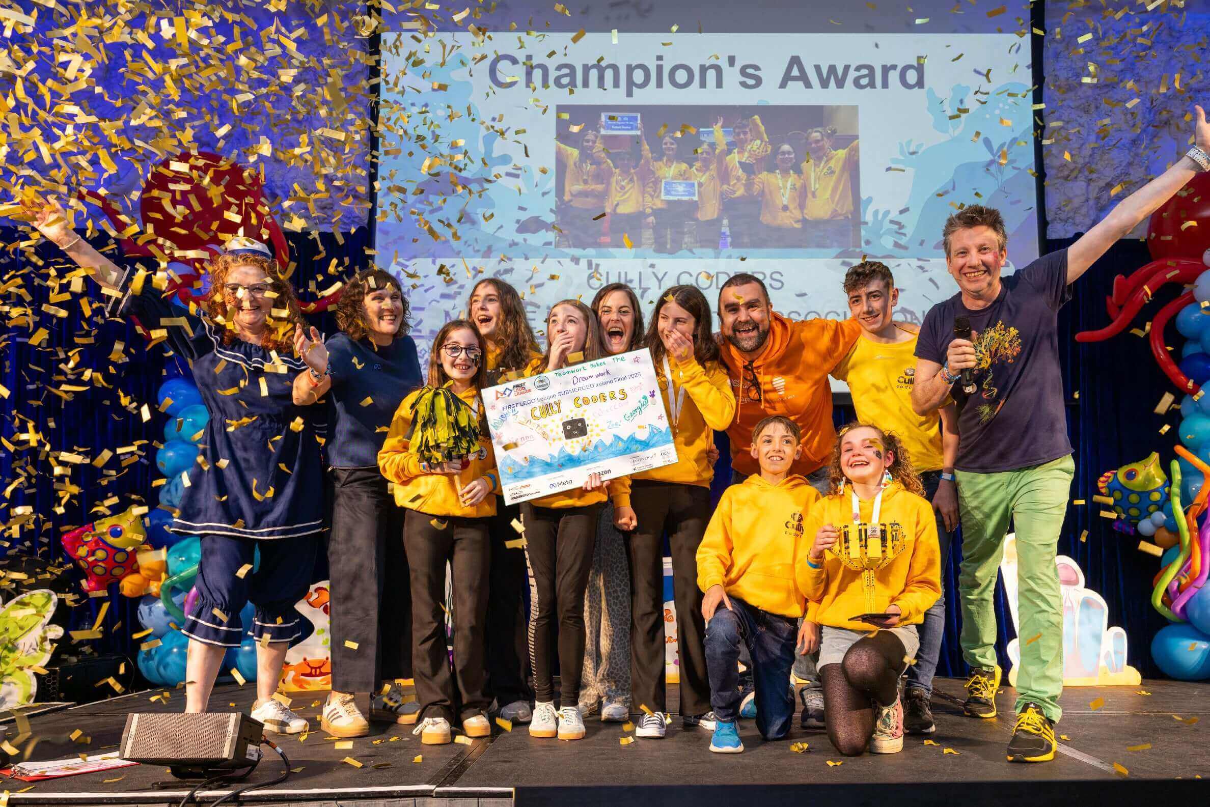 Group celebration at the Champion's Award ceremony, confetti falling, joyful participants holding a large prize check.