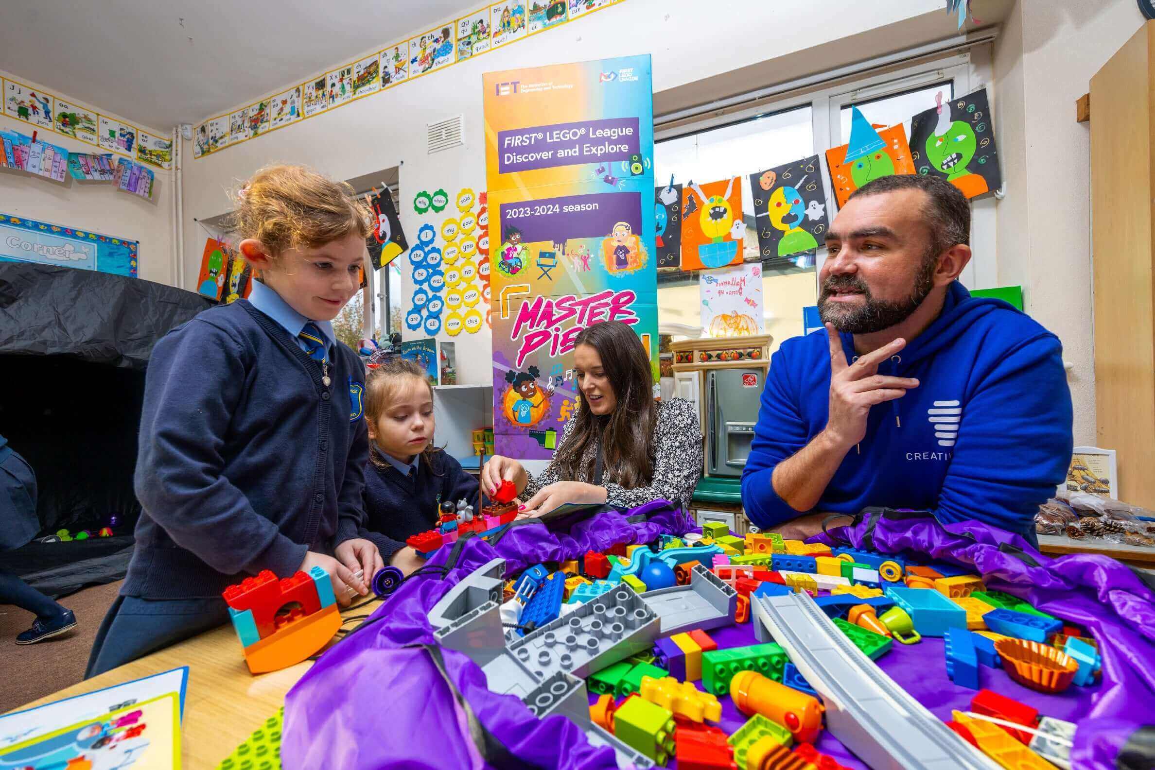 Children and an adult engaging with LEGO bricks in a learning environment, promoting the FIRST LEGO League.