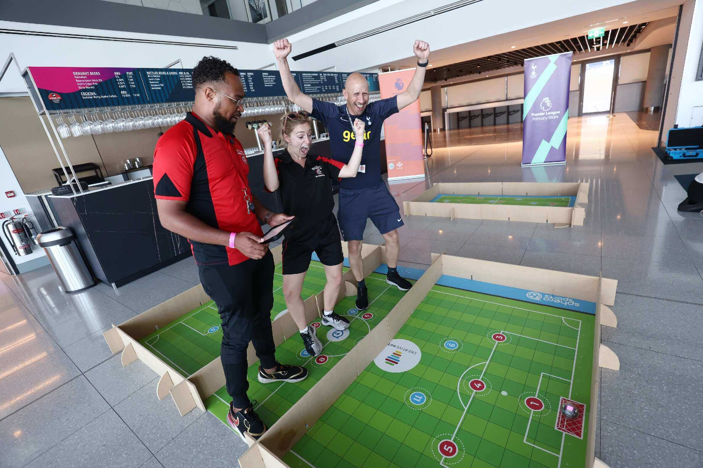 Three excited individuals celebrate while playing a playful sports game in a modern venue.