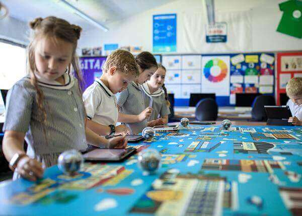 Children engaged in interactive learning with tablets and activities in a colorful classroom setting.