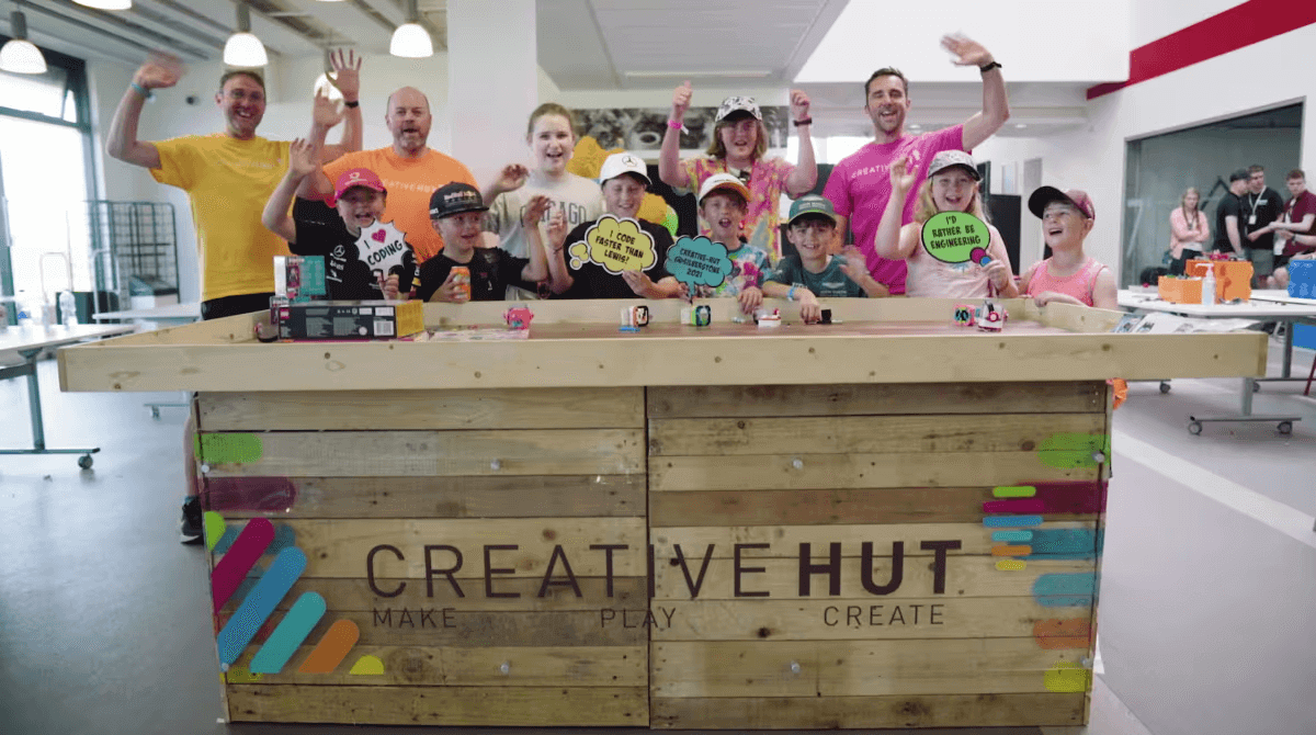 Group of children and adults celebrating at Creative Hut, promoting hands-on learning and creativity.