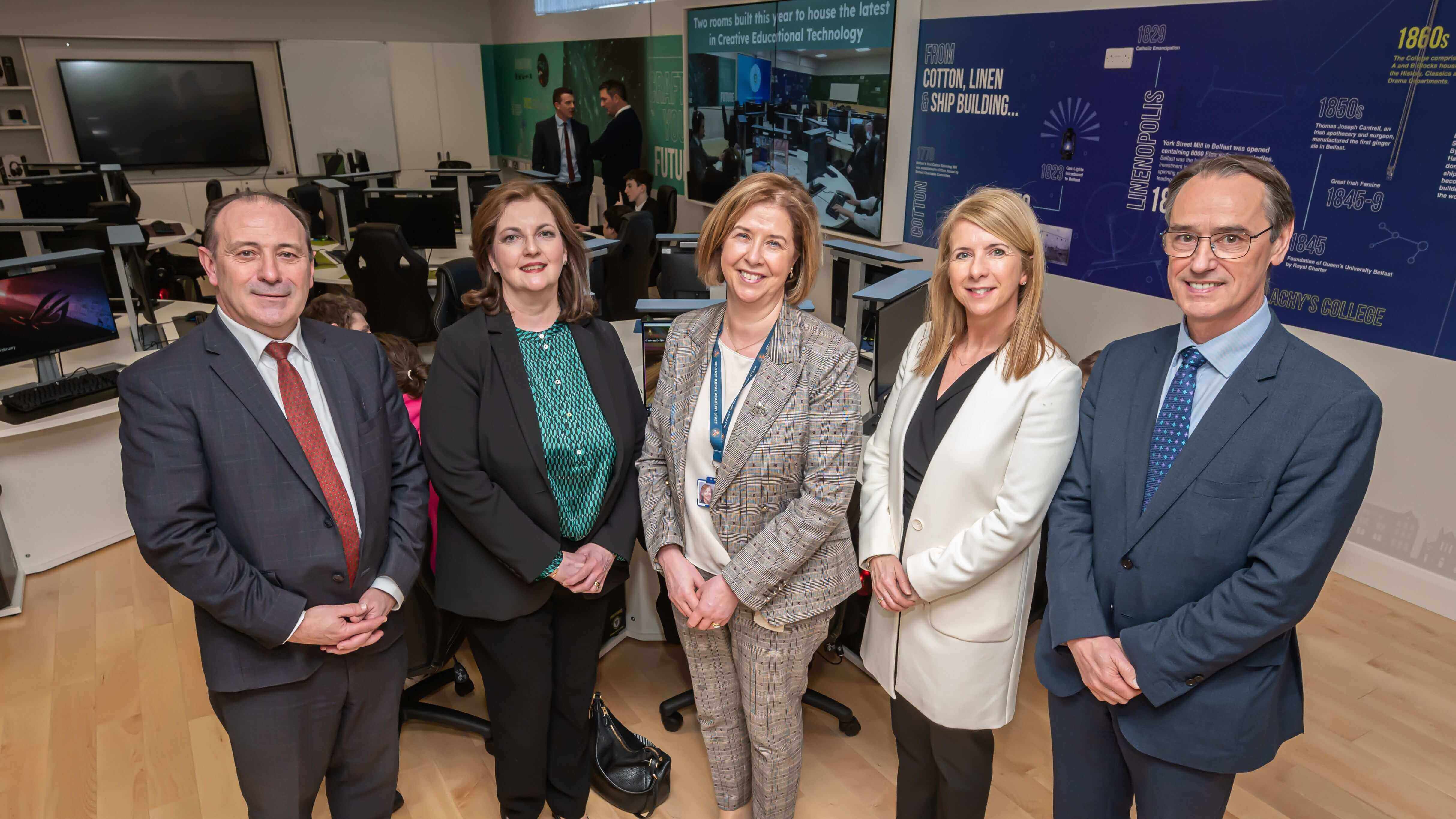 Group of five professionals standing together in a modern office setting, showcasing collaboration and innovation.