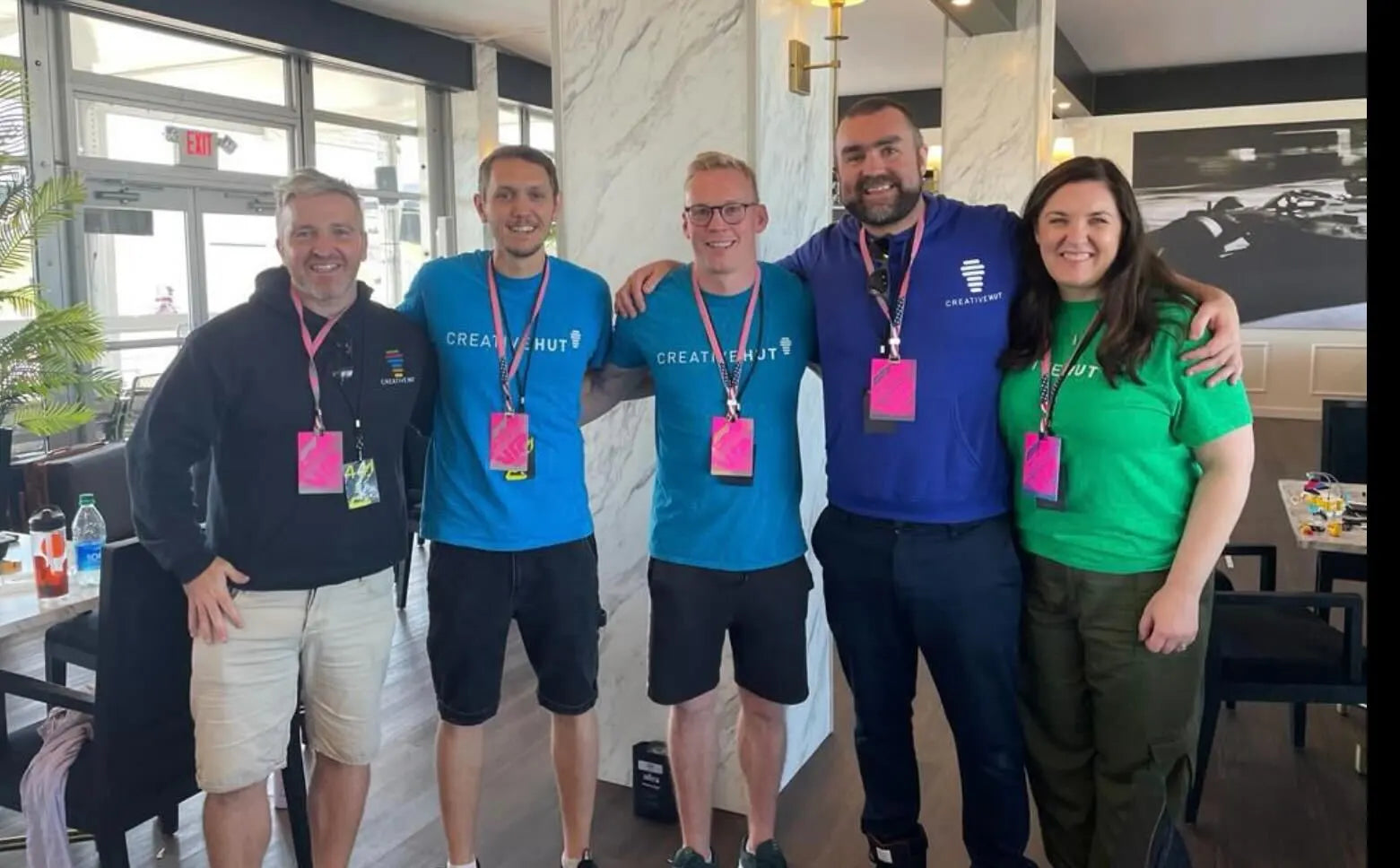 Group photo of five individuals at an event, showcasing team spirit with colorful shirts and tags.