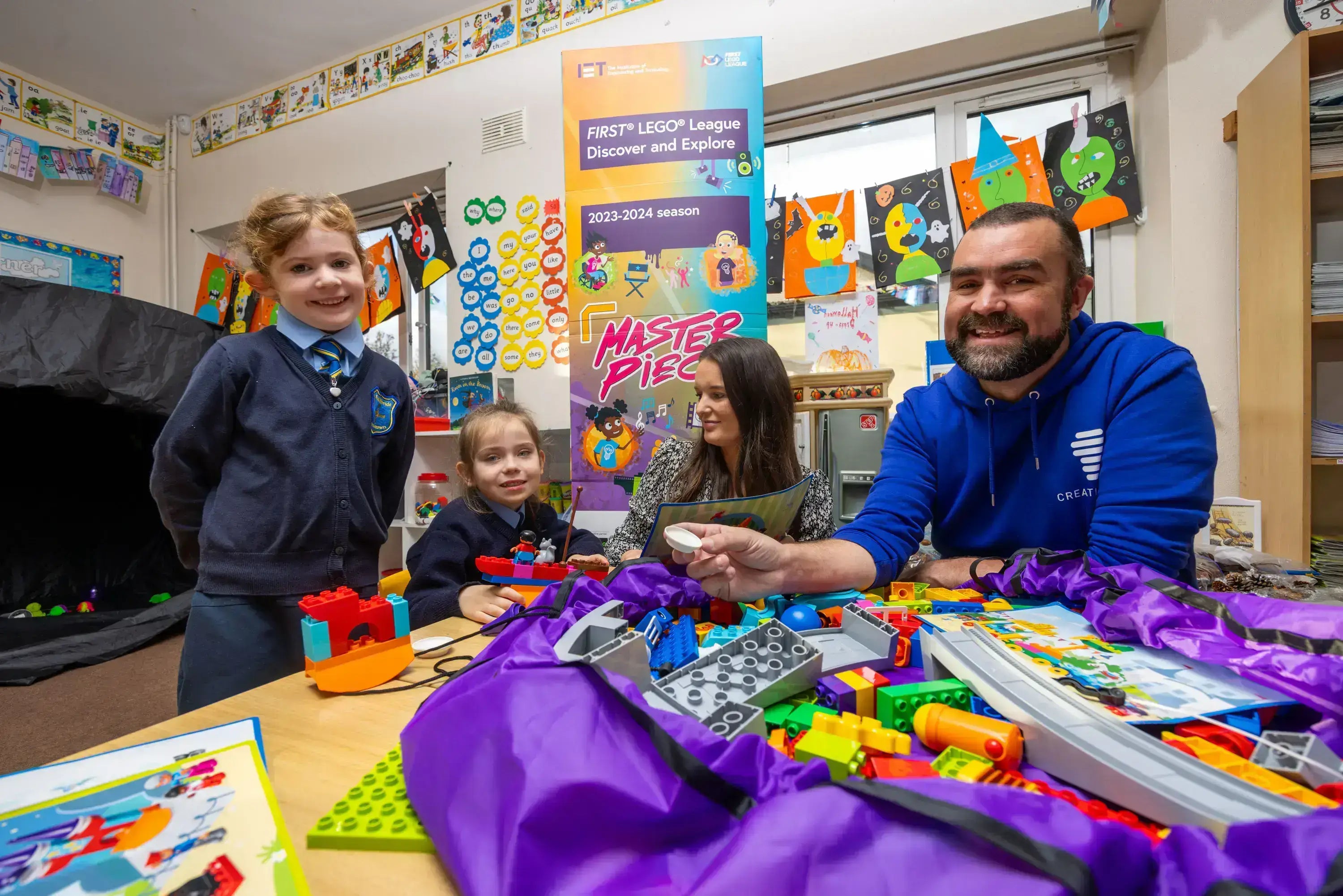 Children and instructor engaging with LEGO robotics in a classroom, promoting STEM learning and creativity.