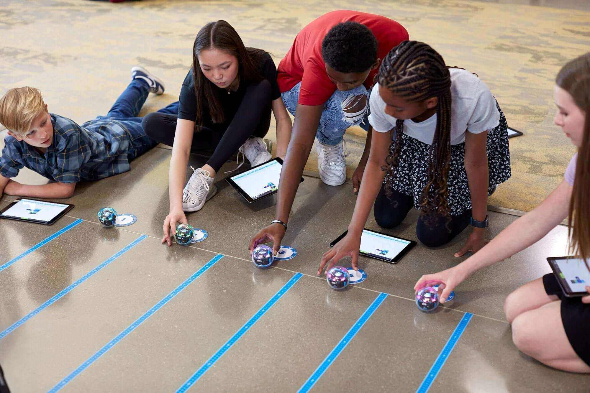 Students engaged in coding activities with robotic toys, promoting hands-on learning and technology in education.
