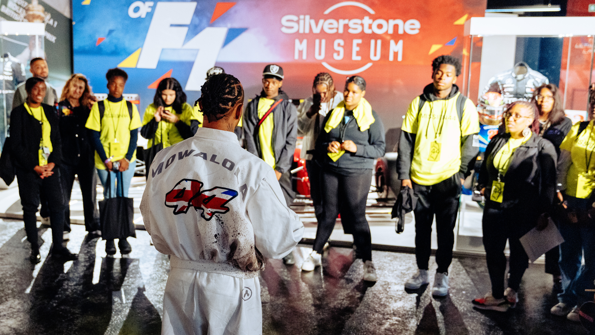 Audience engaged in a talk at the Silverstone Museum with a speaker in a racing suit.