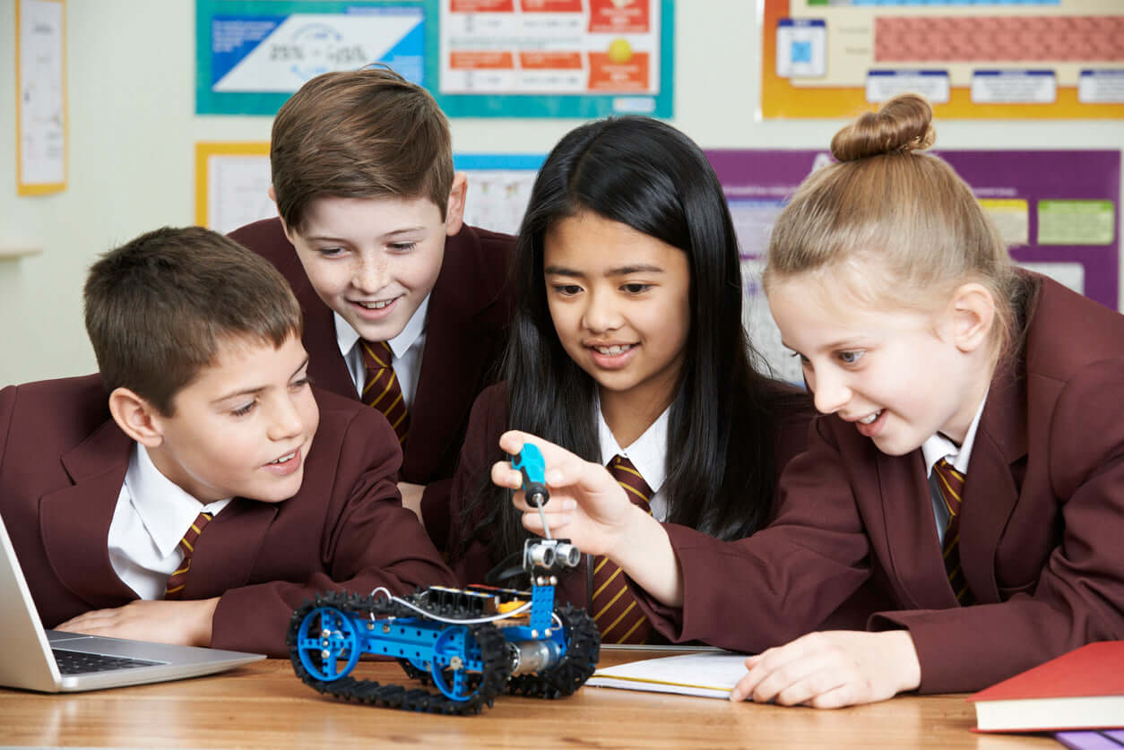 Students engaging in robotics project, excitedly working together with a blue robot on a table in a classroom.
