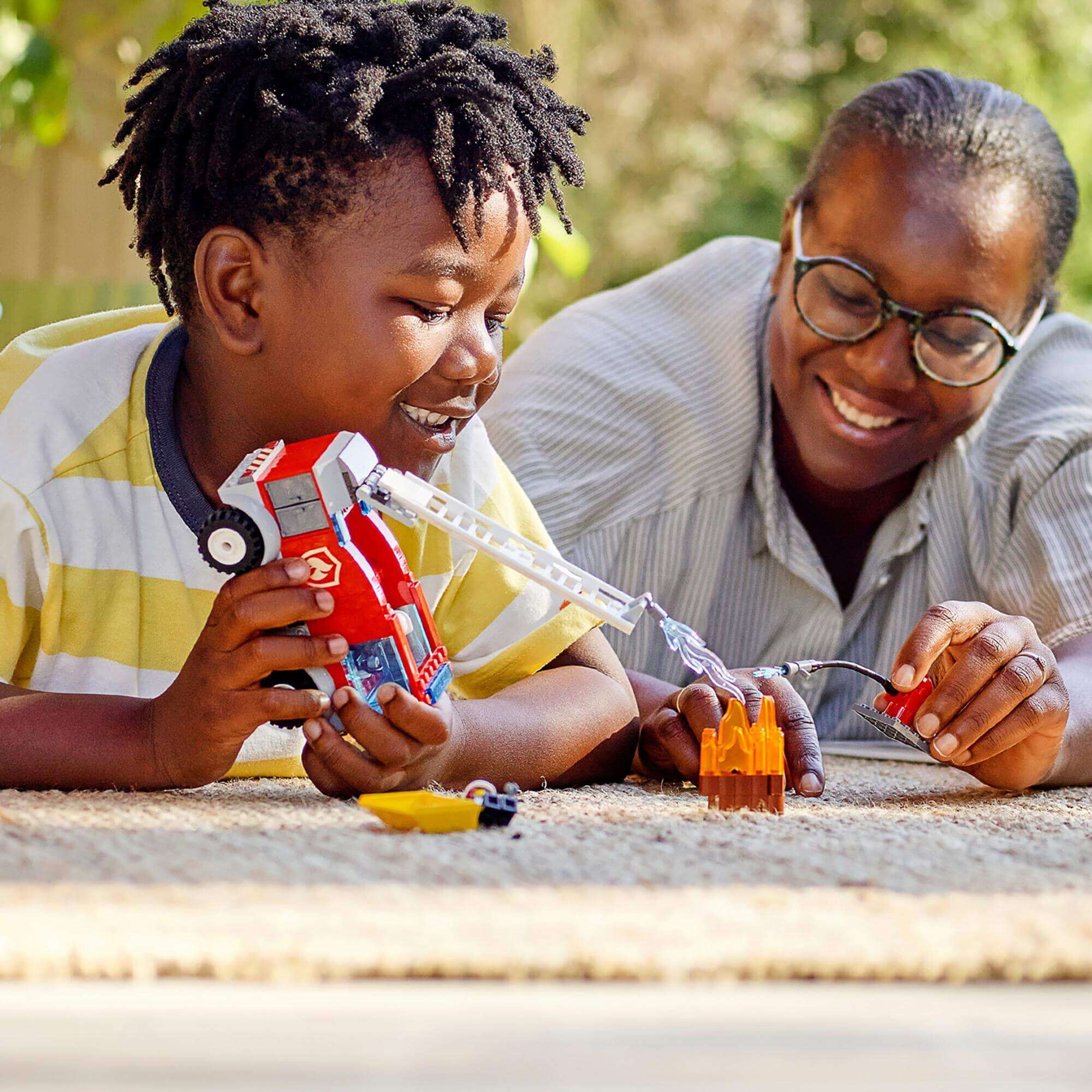 Child and adult joyfully playing with LEGO® City Fire Ladder Truck Toy, fostering imaginative play and bonding.