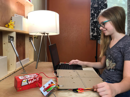 Young girl engaging with Makey Makey STEM Pack on a laptop, exploring hands-on invention and creativity.