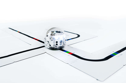 Ozobot Evo robot navigating a color-coded track on educational puzzle pieces, promoting coding skills for students.