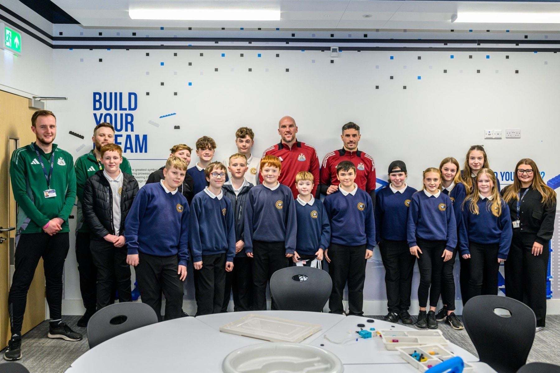 Group photo of students with coaches, promoting team spirit and community involvement in an educational setting.